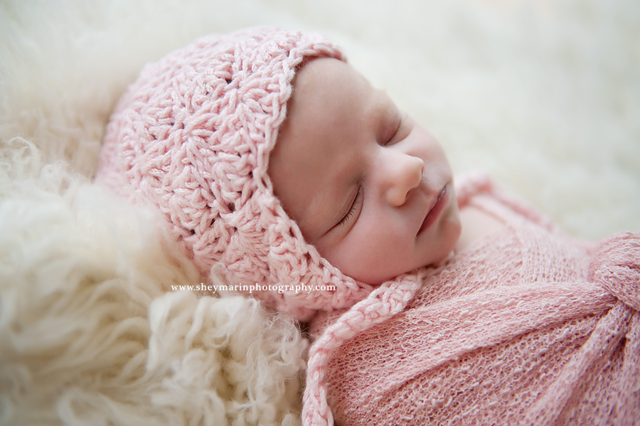 newborn baby girl in pink bonnet