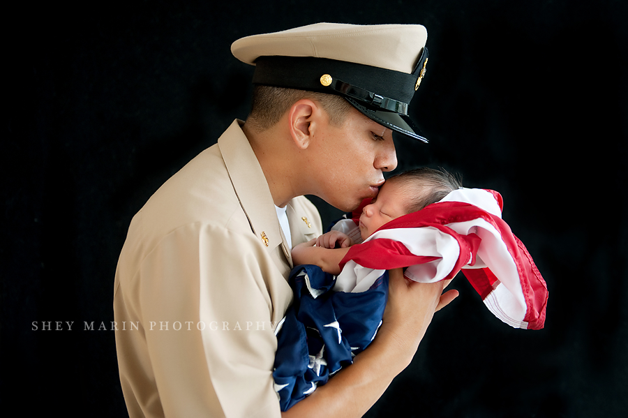 American soldier holding newborn baby in flag