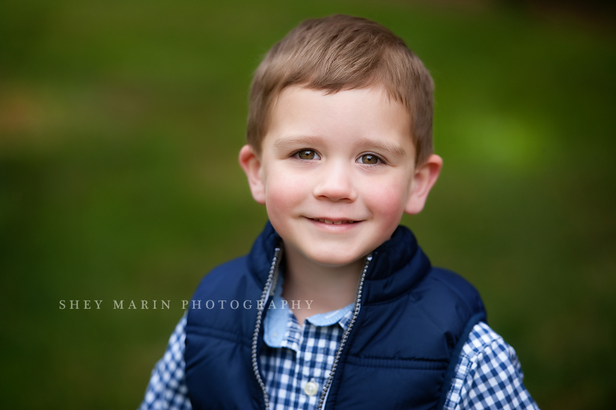 little boy in blue vest smiling