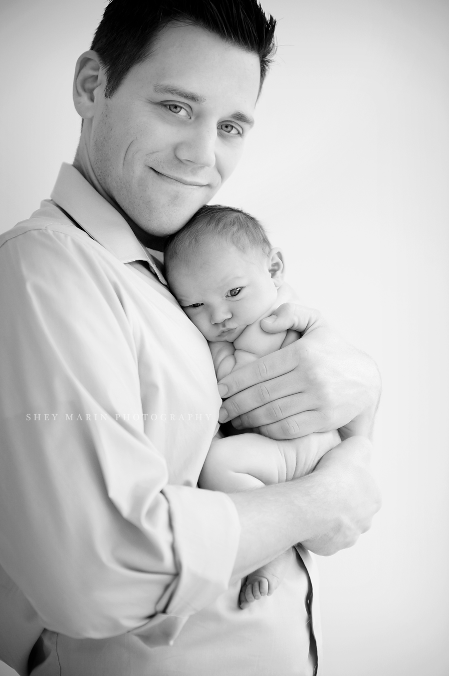 black and white photo of father holding his newborn baby boy