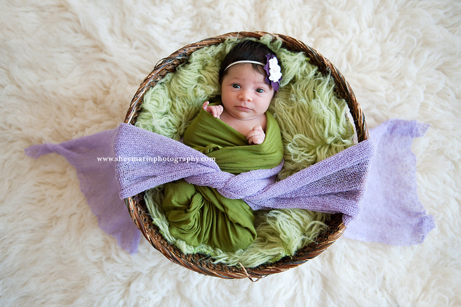 newborn girl in purple and green blankets