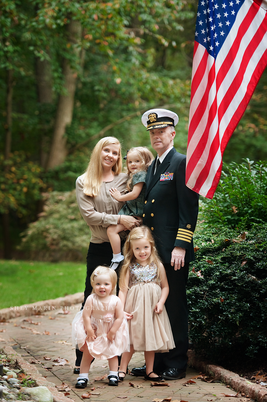 family in front of American flag with soldier father in uniform