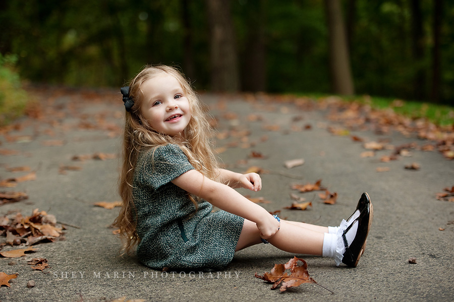 little girl sitting on path smiling