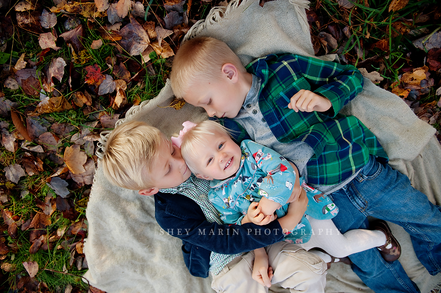 three kids laying in leaves