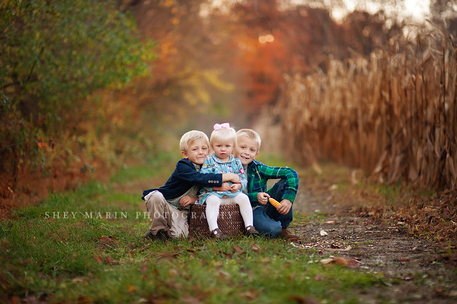 three kids on a farm path during fall