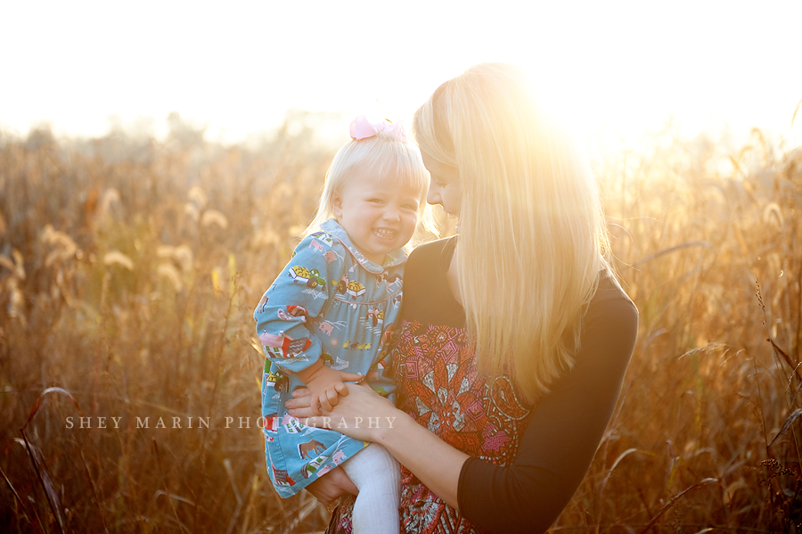 mother and daughter in a corn field with the sunset