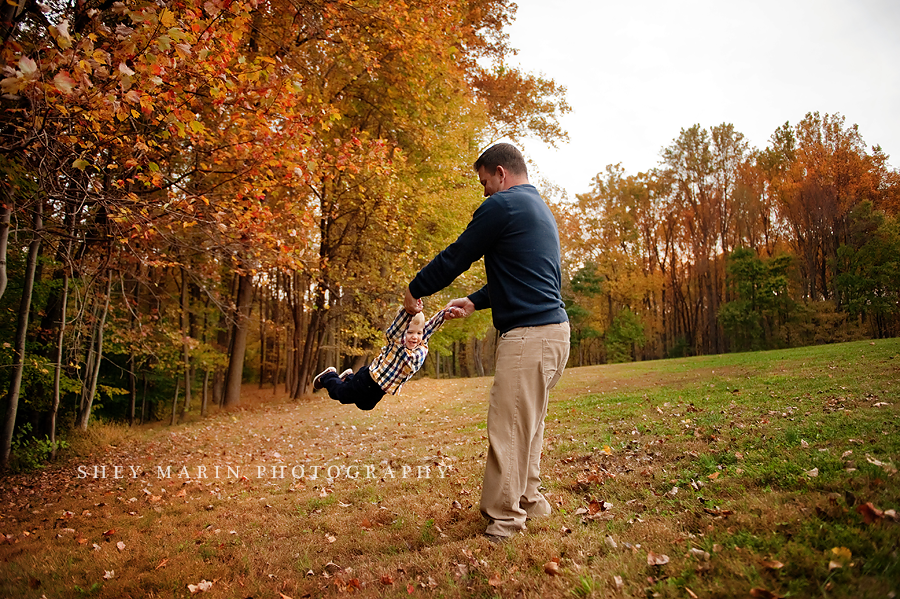 boy swinging with daddy in fall leaves