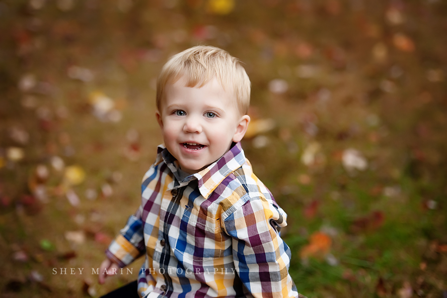 little boy smiling in fall leaves