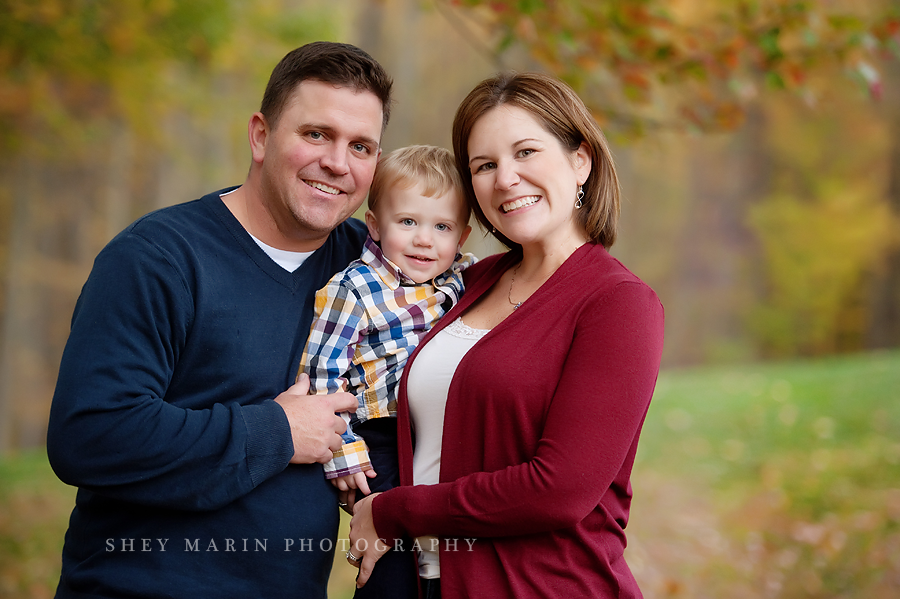 family smiling together in fall foliage