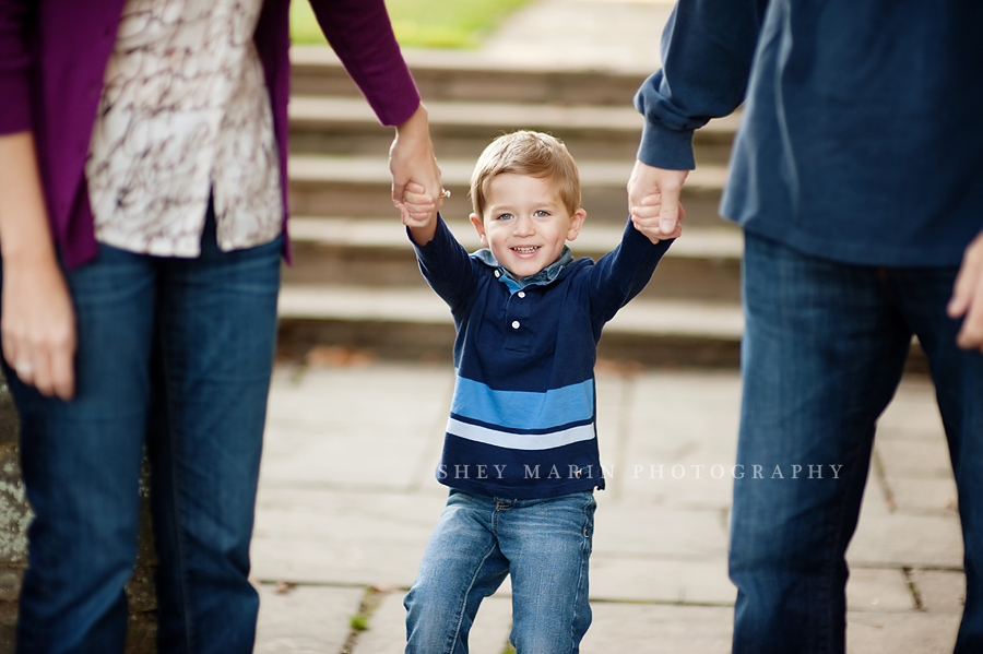 happy boy swinging in parent's arms in Bethesda Maryland