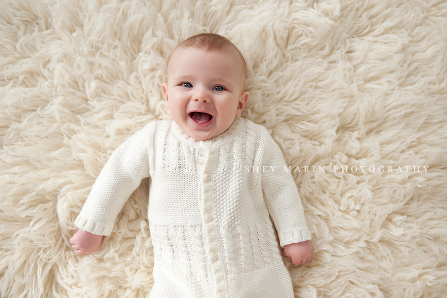 baby boy smiling on cream fur blanket