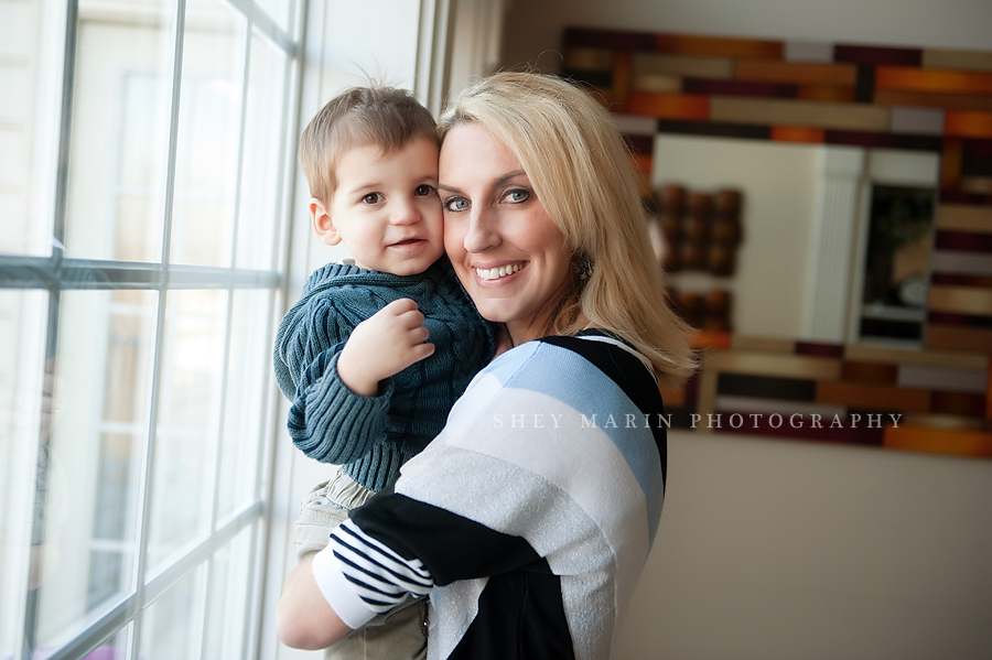 mom hugging son in front of window in lifestyle photosession