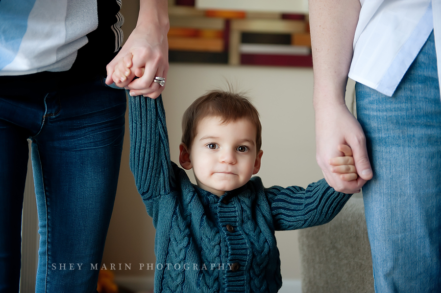 little boy holding parent's hands in their home