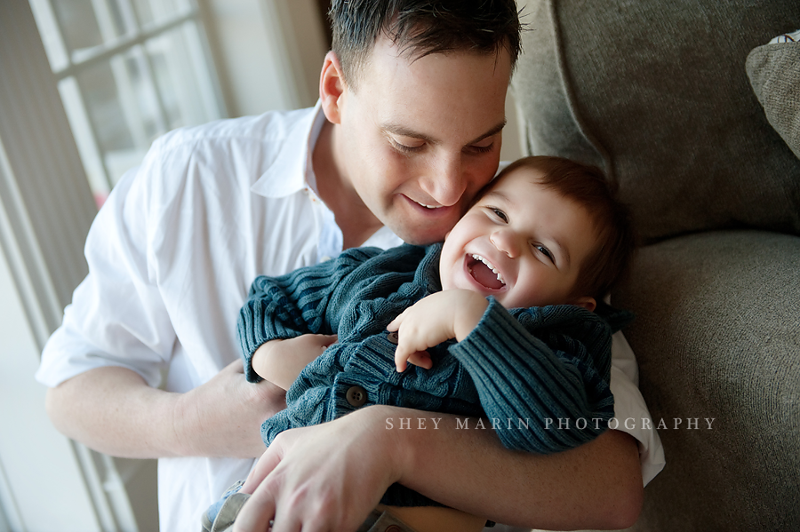 dad tickling son in his arms in their home