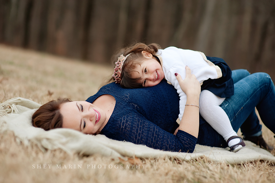 little girl laying on mom in a field with a princess tiara