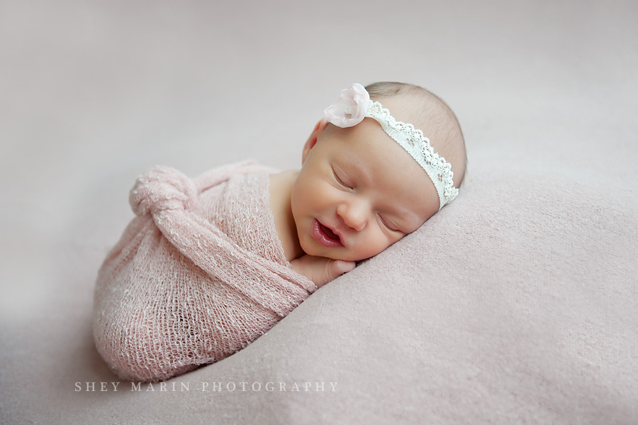 newborn baby girl wrapped in pink cheesecloth