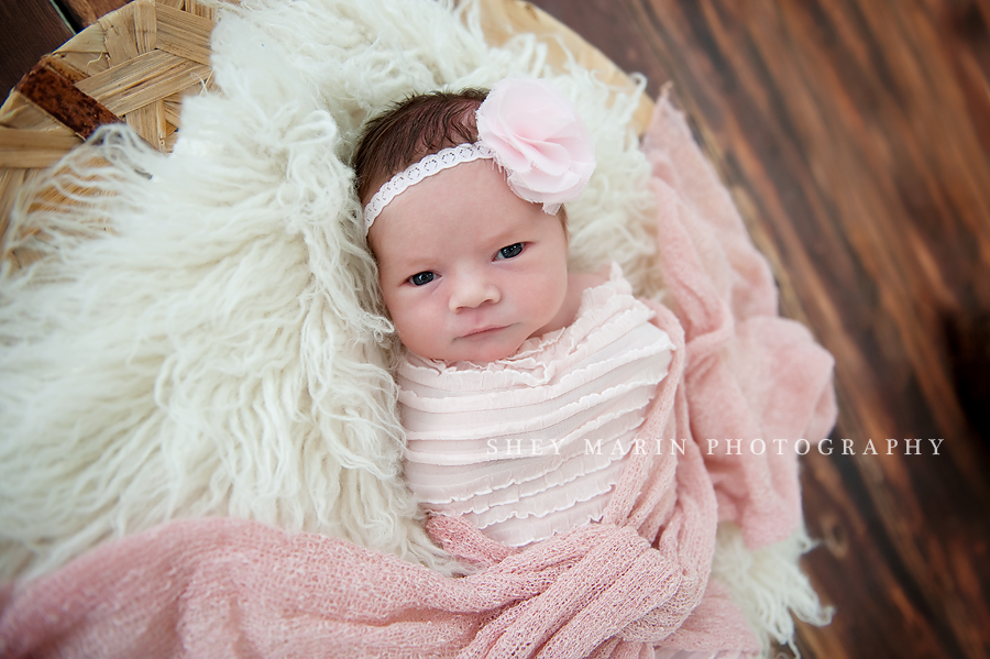 newborn baby girl in pink wrap in basket