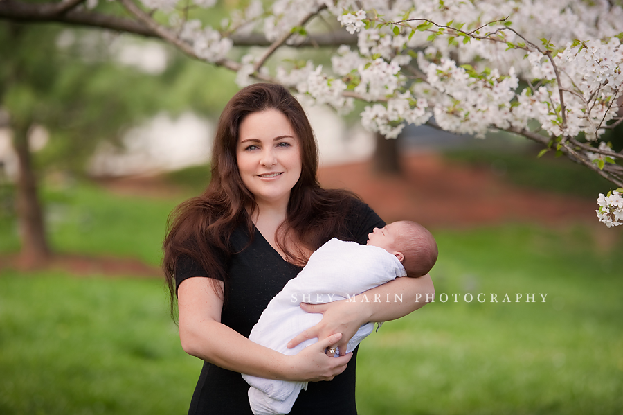 mother holding newborn baby in cherry blossoms