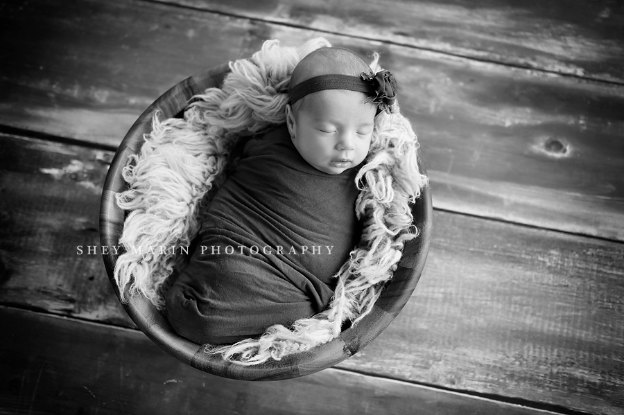 black and white photo of baby girl in basket