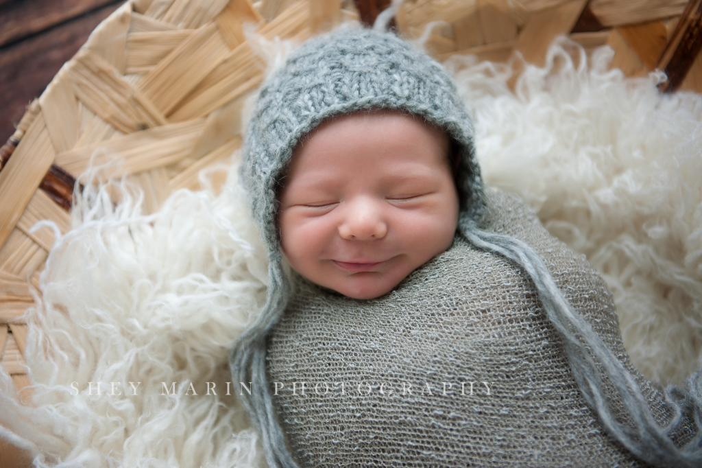 newborn baby boy in grey wrap in basket