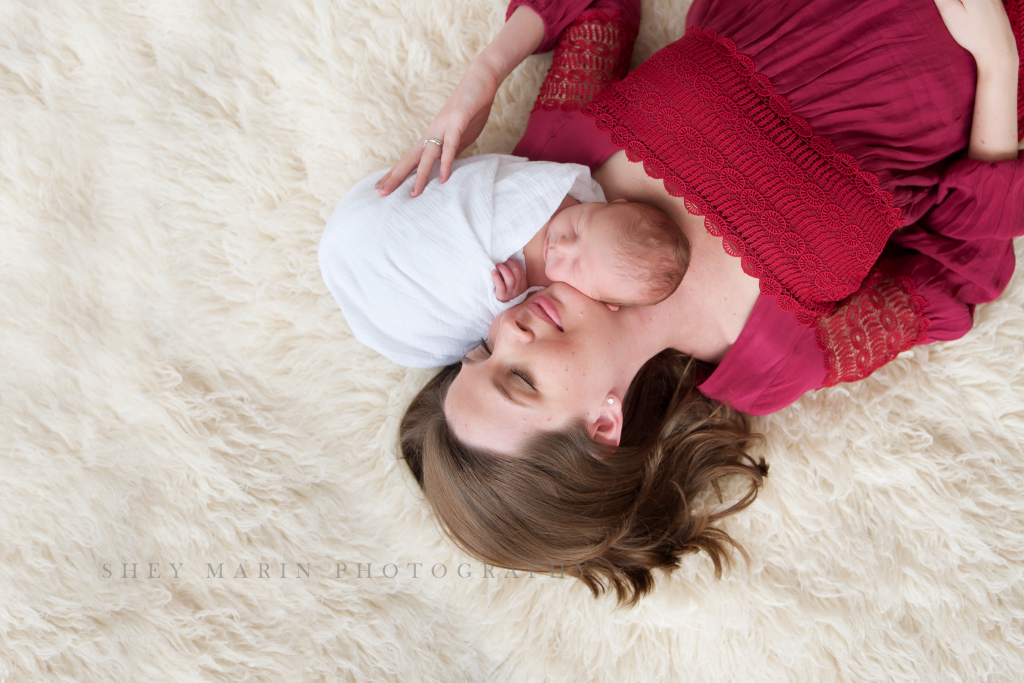 mother and newborn baby laying on cream rug