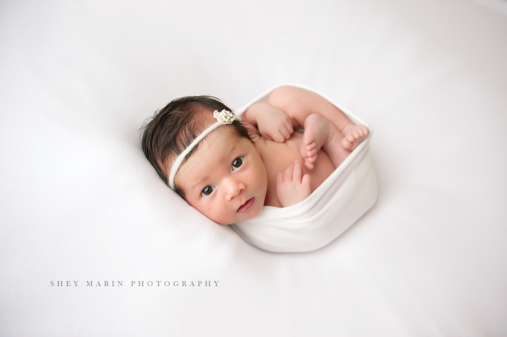 newborn baby girl on white background awake