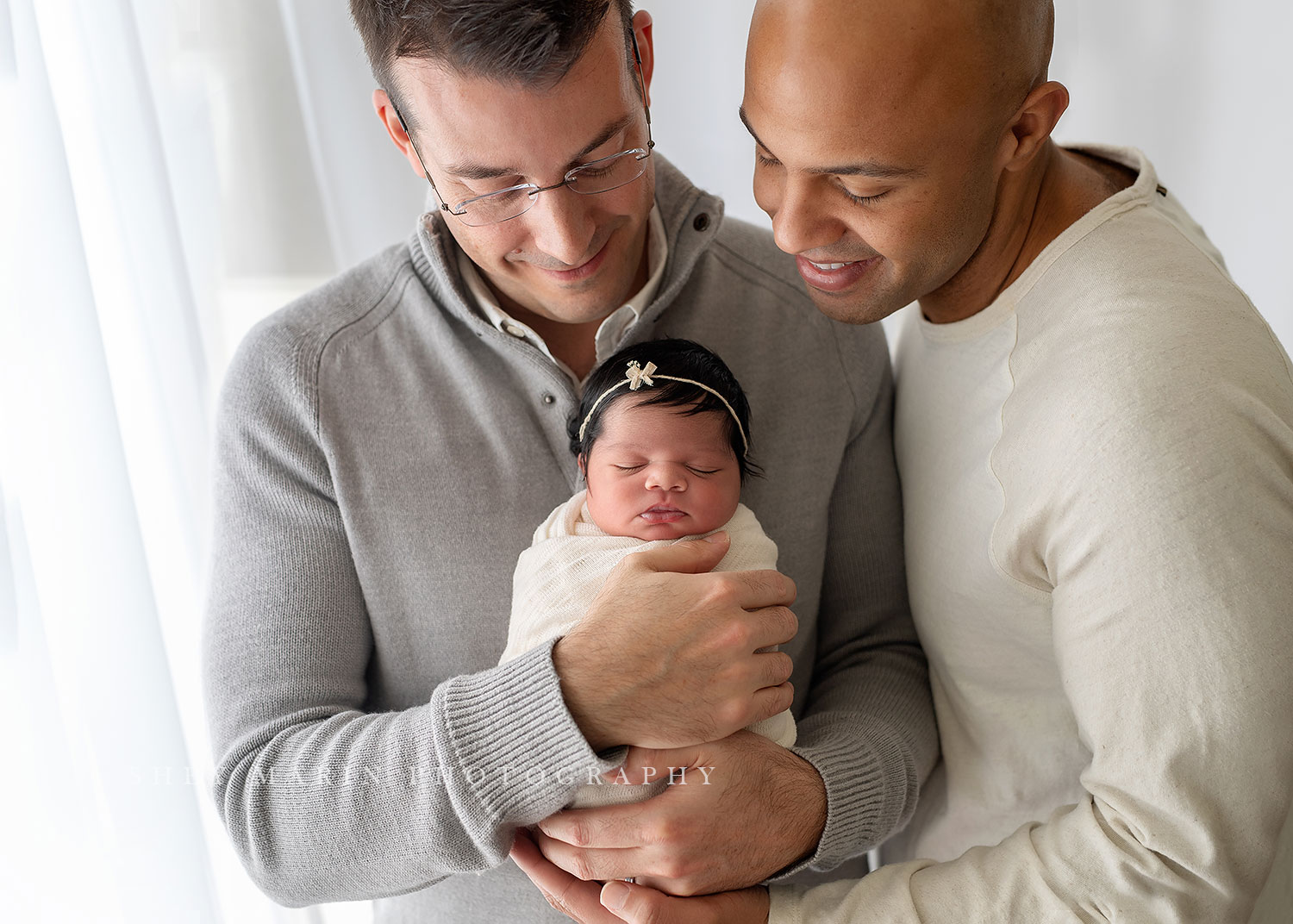 two dads holding their newborn baby