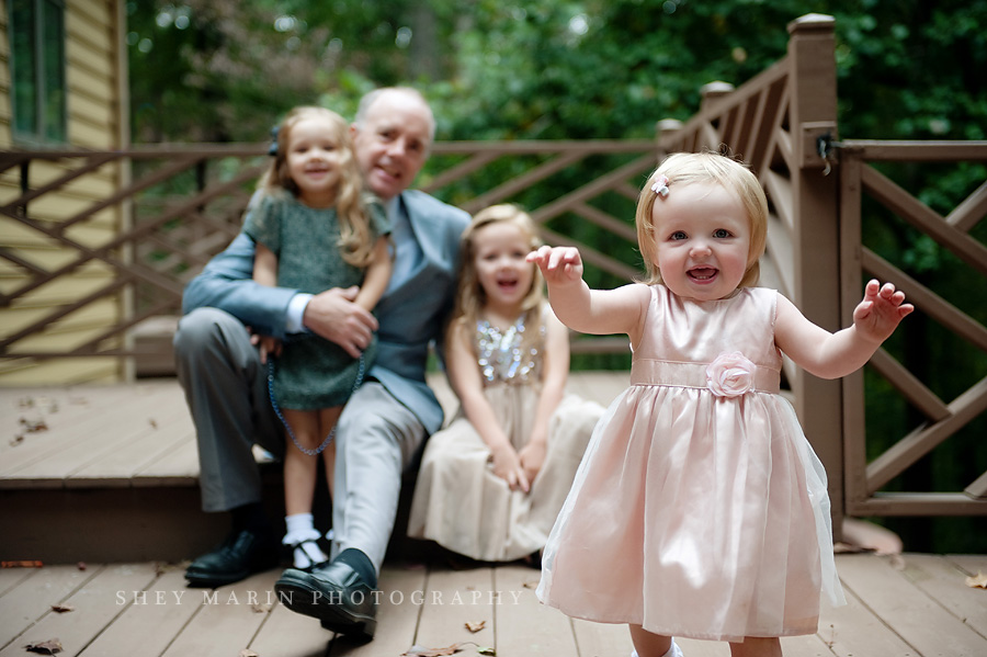 family sitting together with baby girl walking towards camera