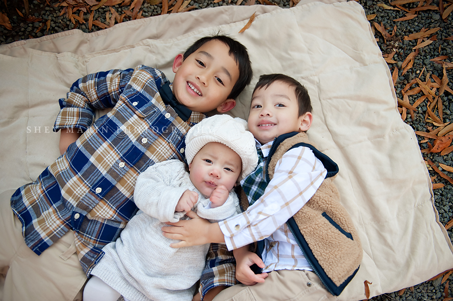 three siblings lying on blanket in winter