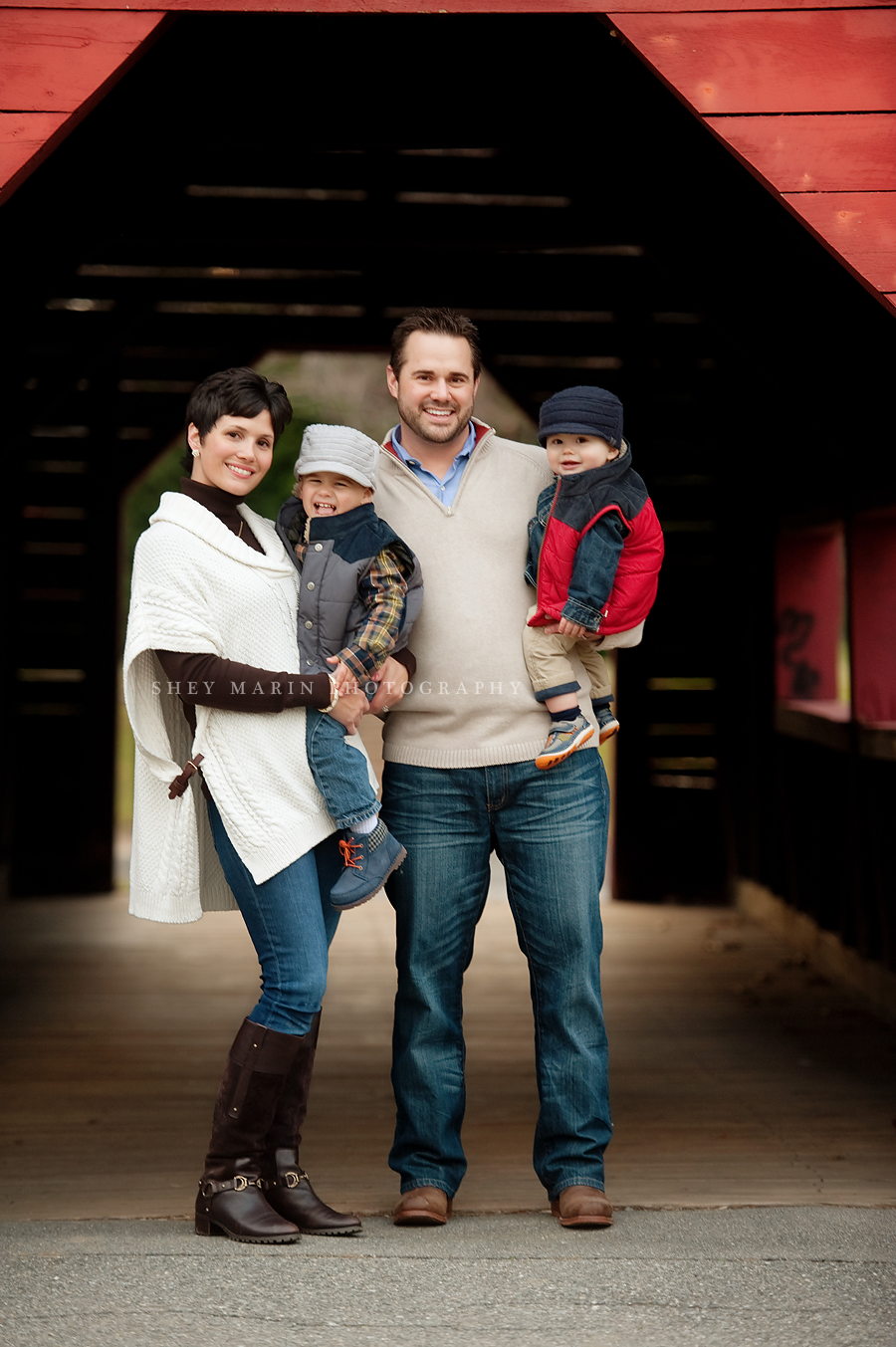 family hugging under a red covered footrbiridge