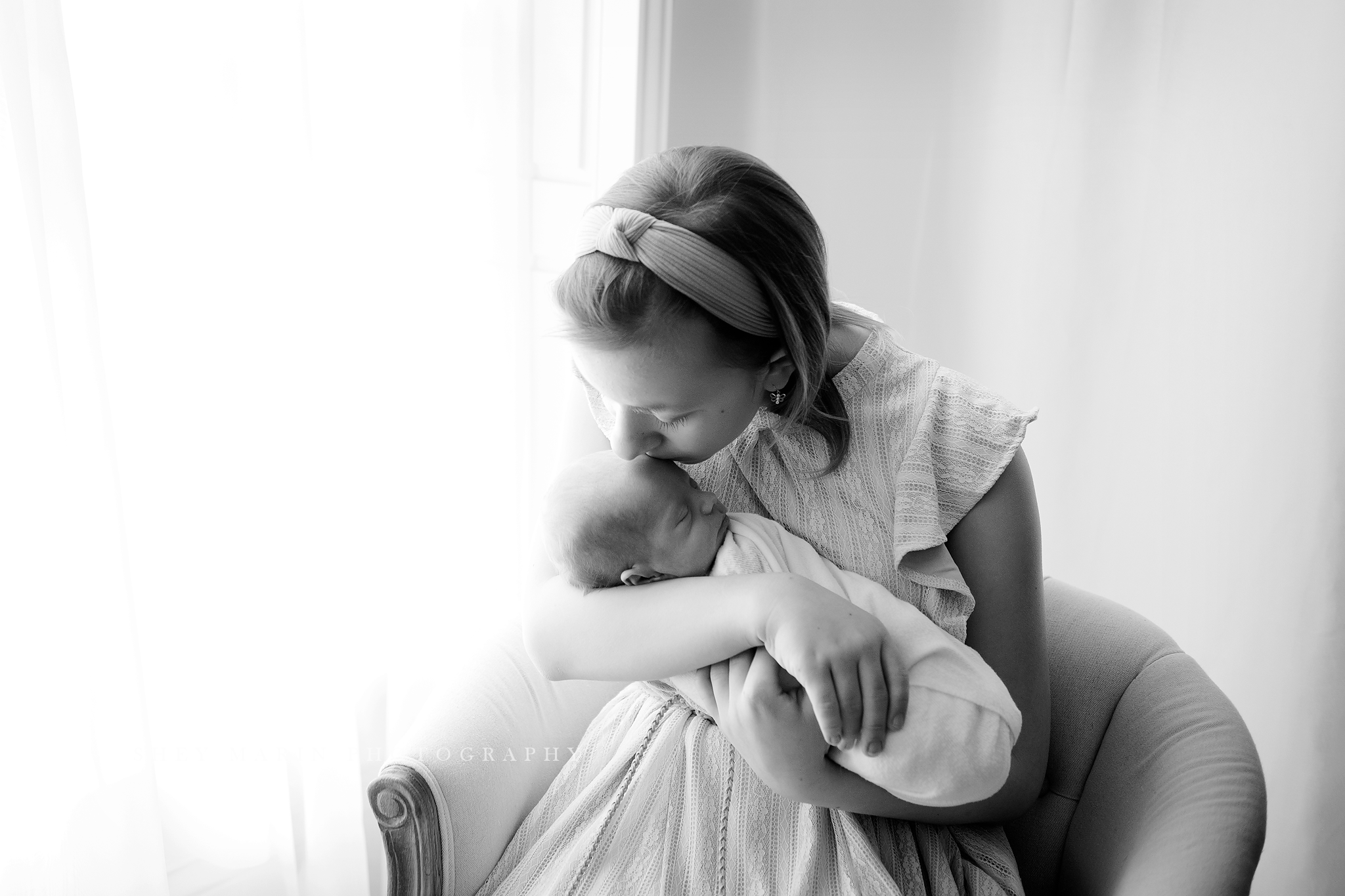 big sister holding baby and kissing his head